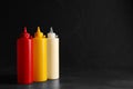 Ketchup, mustard and mayonnaise in squeeze bottles on grey table, space for text Royalty Free Stock Photo