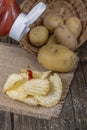 Ketchup is poured over potato chips, with a basket of whole potatoes and grains of salt nearby