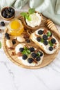 Keto diet sandwiches, snack. Sweet bruschetta with cheese and berries blackberry ricotta and honey on marble table. Healthy