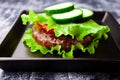 Keto paleo bunless burger lettuce wrapped no bread stacked with beef meat cutlet, tomato, cucumber.