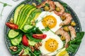 Ketogenic diet breakfast shrimps, prawns, soft fried egg, fresh salad, tomatoes, cucumbers and avocado on a dark background. Keto Royalty Free Stock Photo