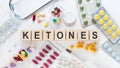 KETONES medicine word on wooden blocks on a desk. Medical concept with pills, vitamins, stethoscope and syringe on the background