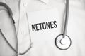 ketones text on white paper on the white background. stethoscope ,glasses and keyboard