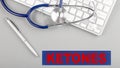 KETONES word with stethoscope on keyboard on grey background