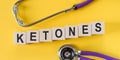 Ketones - word on wooden cubes on yellow background with stethoscope Royalty Free Stock Photo