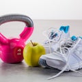 Kettle bell with sneakers and healthy apple over gym floor