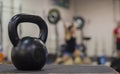 A cast iron kettle bell with a young women weight lifting in the background Royalty Free Stock Photo