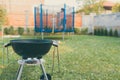 Kettle Charcoal BBQ Barbecue Grill in garden or backyard. Blurred Outdoor trampoline in the background. Family Home