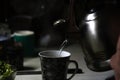 Kettle pouring into mug. Kettle pouring boiling water into a cup during breakfast in morning. Dark night. Out of focus Royalty Free Stock Photo