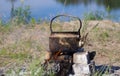 Kettle in soot hung over the fire in the campfire on fire