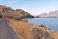 Trail along lake with autumn grasses and leaves and mountains in distance with sunset light