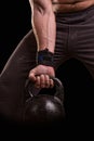 Kettlebell on a black background. The fist of an athlete clutching kettlebell