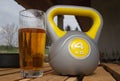 Kettlebell and glass of beer on a wooden table.