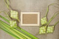 Ketupat rice dumpling with wooden frame on jute texture background.