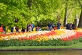 Keukenhof, Netherlands - May, 2018: Tourists and visitors walking throung colorful tulips near the river bank in Keukenhof park in