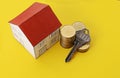 Key with coins stack and paper house on yellow backgrounds