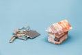 Key and house keychain on real estate with origami from russian rubles. Light blue background. Copy space. Concept of