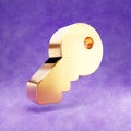 Key icon. Gold glossy Key symbol isolated on violet velvet background. Royalty Free Stock Photo