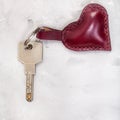 Key with leather heart shape trinket on concrete Royalty Free Stock Photo