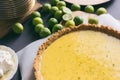 Key lime pie with graham cracker crust resting on parchment paper. Overhead view with extra key limes, plates and whipped cream. Royalty Free Stock Photo