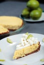 Key Lime Pie on grey cloth with pie and limes in back Royalty Free Stock Photo