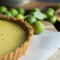 Detailed view of a key lime pie with graham cracker crust and lime zest. Key limes in the background. Royalty Free Stock Photo