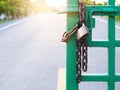 Key lock with rusty iron chain on green gate fence door on road