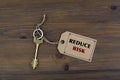 Key and a note on a wooden table with text - REDUCE RISK