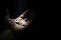 A key in an open palm in the dark under a beam of light. Space for text. Royalty Free Stock Photo