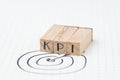 Key Performance Indicator, KPI concept, small wooden stamp combine the acronym KPI with hand draw arrow and target on white grid