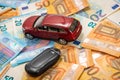 Key and red toy car on pile of euro banknotes, buy or sell a car, rent a car or insurance concept Royalty Free Stock Photo