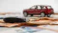 Key and red toy car on pile of euro banknotes, buy or sell a car, rent a car or insurance concept Royalty Free Stock Photo