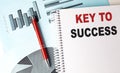 KEY SUCCESS text on a notebook with pen on a chart background Royalty Free Stock Photo