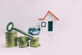 Key on top of a stack of coins with a blurred house and car on the background: real estate, property, mortgage, concept Royalty Free Stock Photo