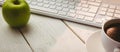 Keyboard with coffee cup and green apple on table Royalty Free Stock Photo