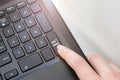 Keyboard corner of a black laptop, lit by sunlight, with a female finger clicking on a don`t panic button Royalty Free Stock Photo