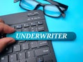 Keyboard and glasses with the word UNDERWRITER on a blue background.