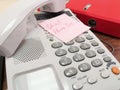 On the keyboard of the landline telephone lies a pink square leaflet with the inscription in red ink Chief, Phone sex Royalty Free Stock Photo