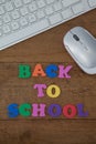 Keyboard, mouse and block letter with back to work text on wooden background