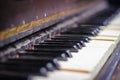 The keyboard of a very old abandoned piano is covered with dust, some keys have dropped, some are absent