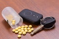 Keychain car alarms, car keys and blisters of medical pills on wooden table