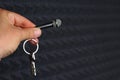 Keychain with keys in the form of a microphone in a hand on a blurred background of a black studio paralon