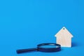 Keychain Wooden house and magnifier on a blue background.