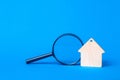 Keychain Wooden house and magnifier on a blue background.