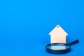 Keychain Wooden house and magnifier on a blue background.