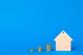 Keychain Wooden house and stacks of coins on a blue background.