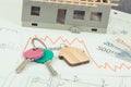 Keys, euro and downward graphs representing crisis of real estate market. Reduced housing prices. House under construction