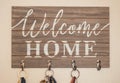 keys hanging on wooden and metal key hook with welcome home message