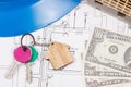 Keys with home shape, currencies dollar and house under construction on electrical construction drawings. Building or buying home Royalty Free Stock Photo