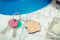 Keys with home shape, currencies dollar and house under construction on electrical construction drawings. Building or buying home Royalty Free Stock Photo